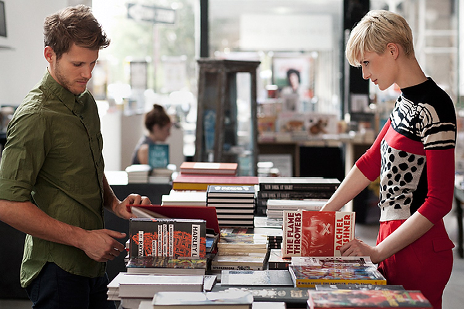 Two strangers reaching toward the same stack of books in a bookshop